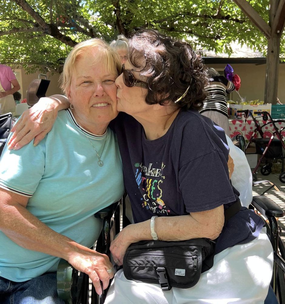 Two friends embracing outdoors on a sunny day.