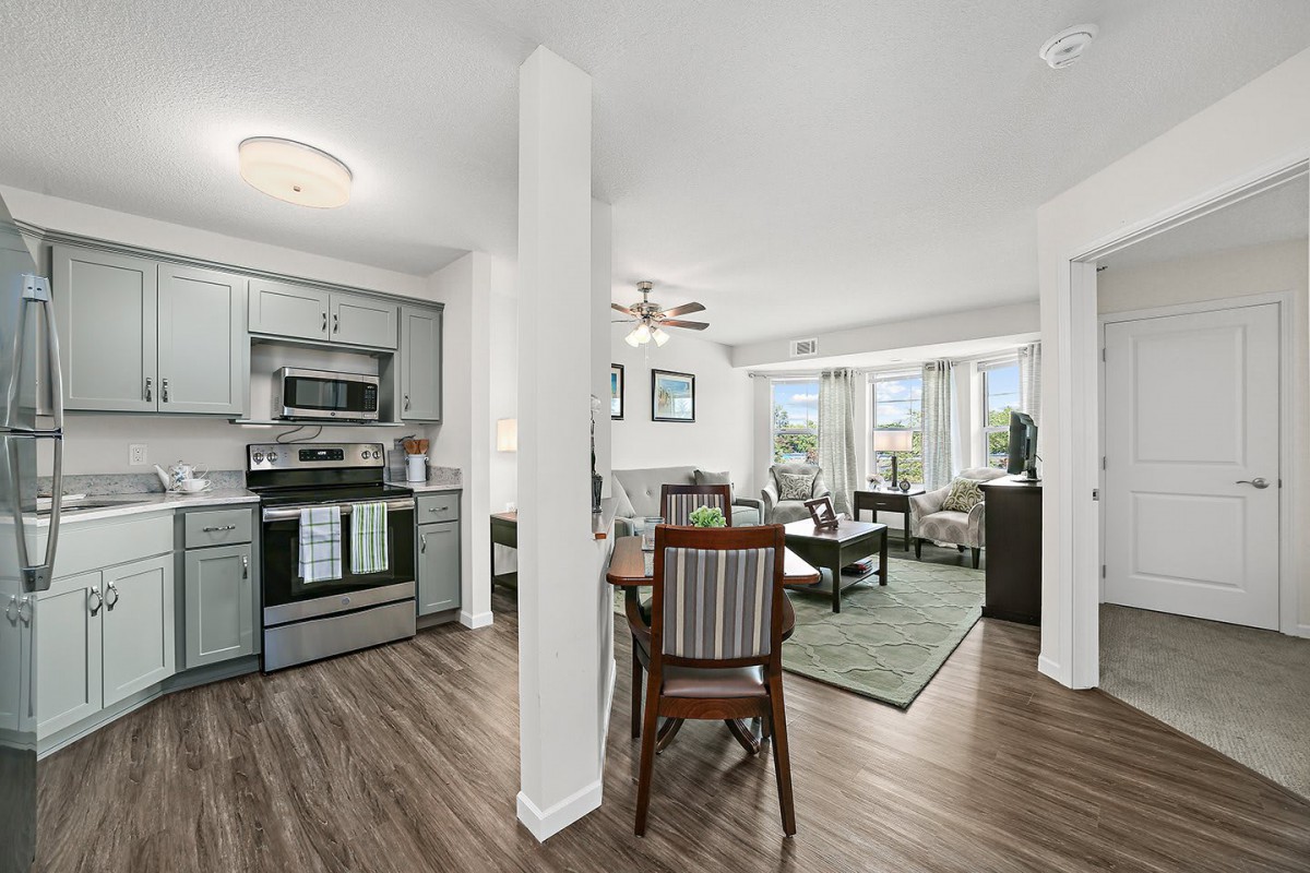 Modern open floor plan with a kitchen, dining area, and living room featuring hardwood floors and contemporary furnishings.
