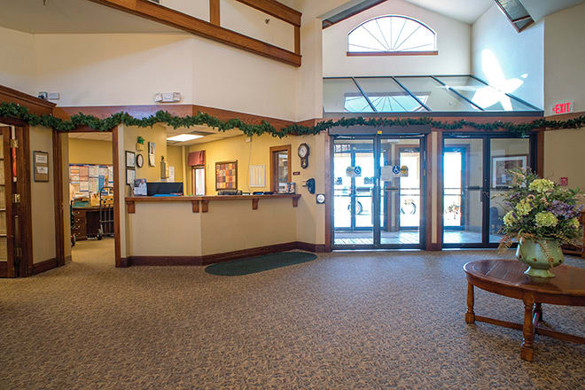A spacious lobby with a reception desk and seating area illuminated by natural light.