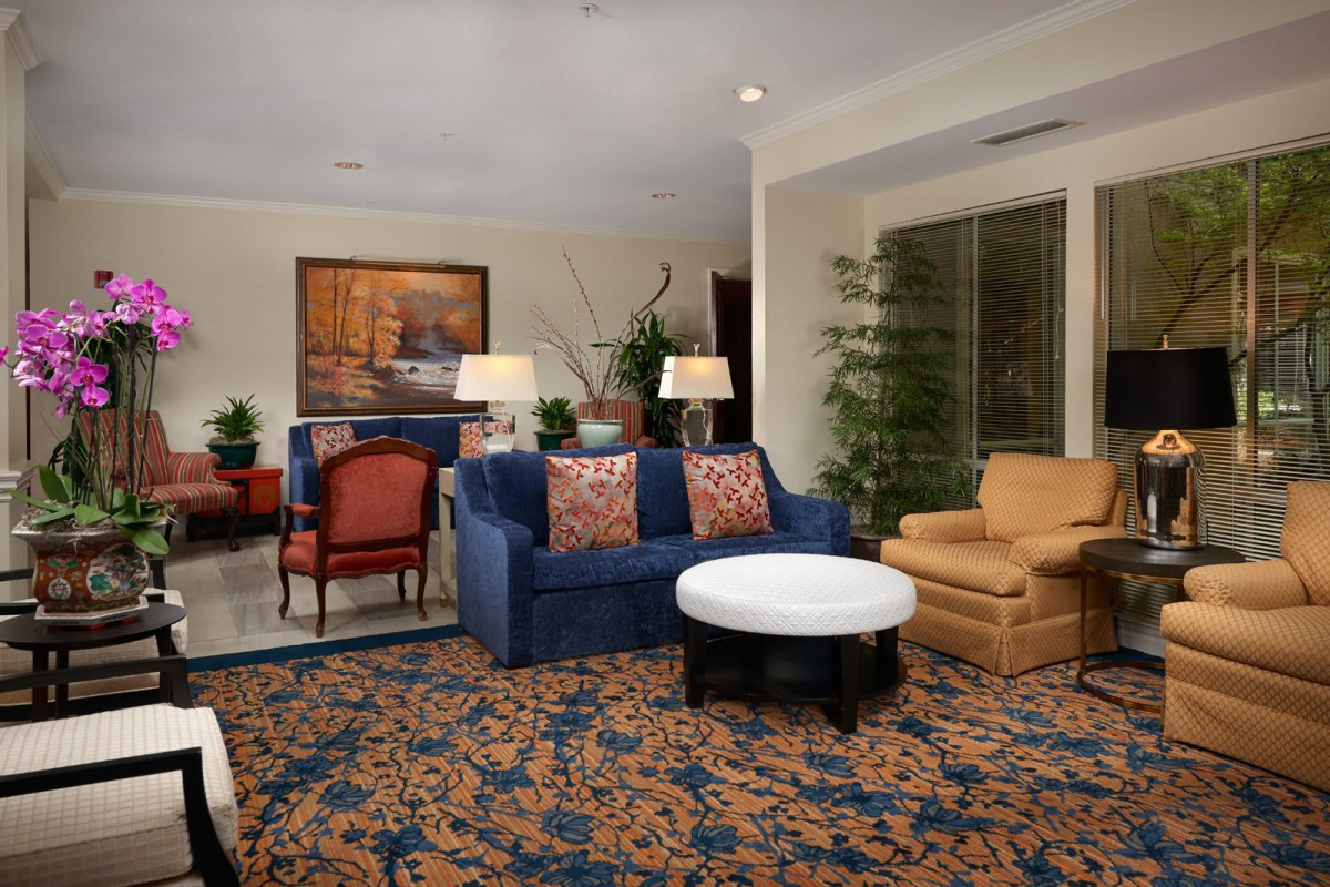 A cozy living room with a blue sofa, orange armchair, and decorative carpet.