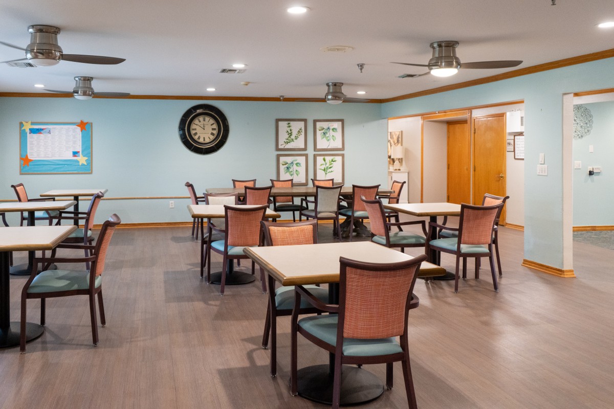 A recreational dining area with tables, chairs, and a dartboard on the wall.
