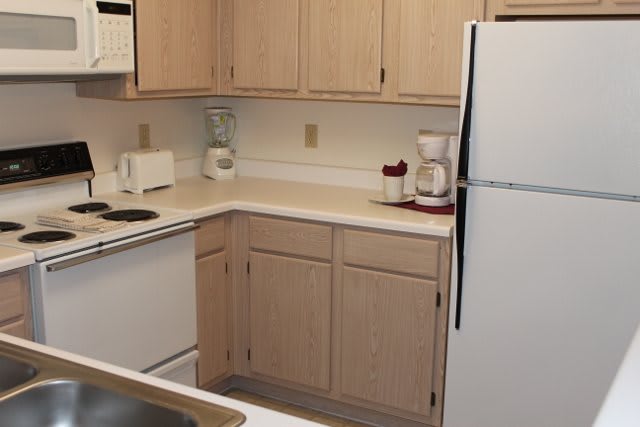 A cozy kitchen corner with appliances on the countertop and light wooden cabinets.
