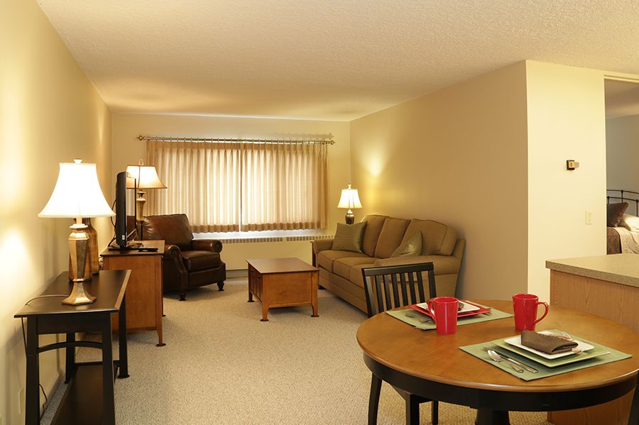 A cozy living room with a sofa, coffee table, and dining area.