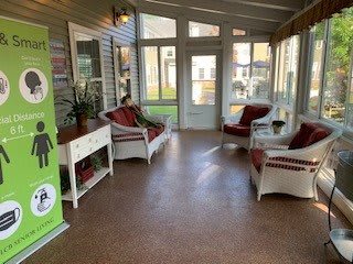 A cozy sunroom with seating and large windows.