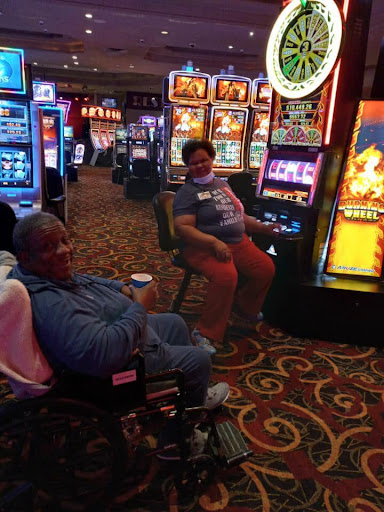 Two individuals enjoying their time at a casino, playing on slot machines.