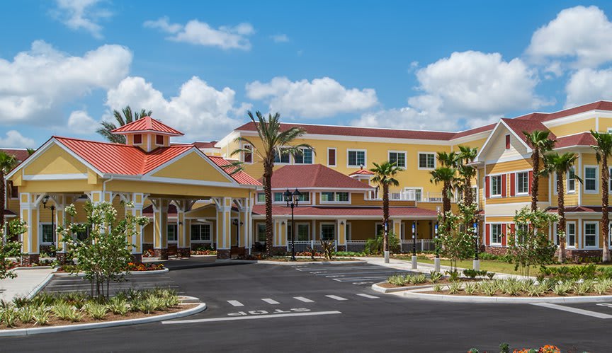 A modern resort building featuring vibrant colors and surrounded by palm trees under a clear blue sky.