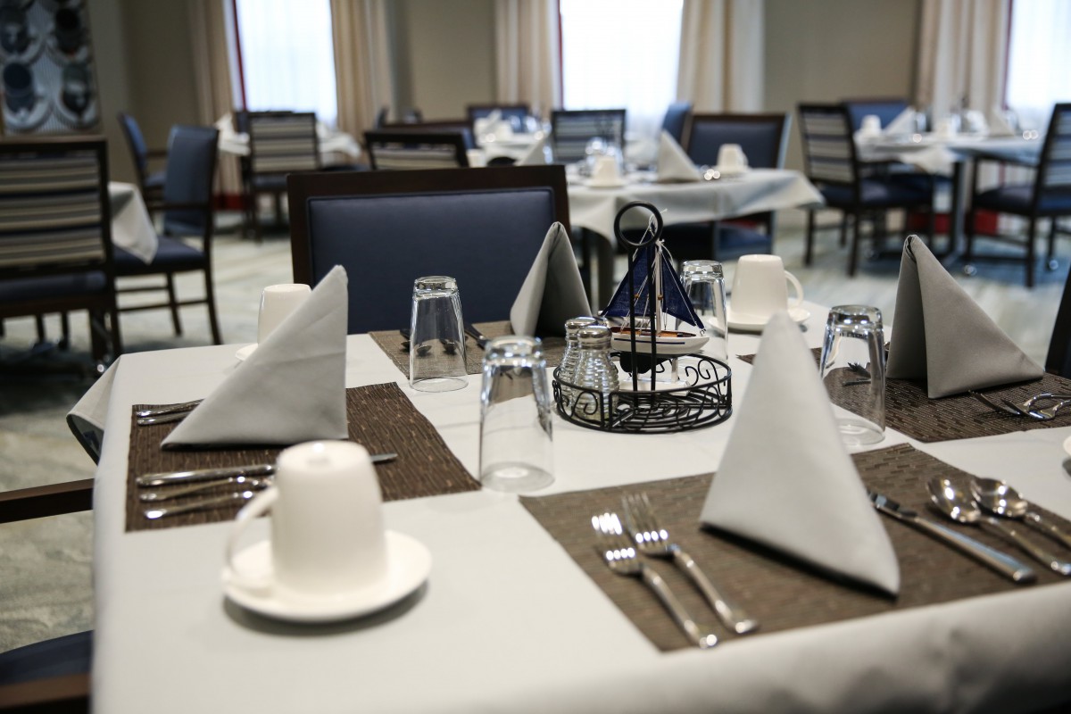 A neatly arranged dining table in a restaurant with glasses, cutlery, and napkins.