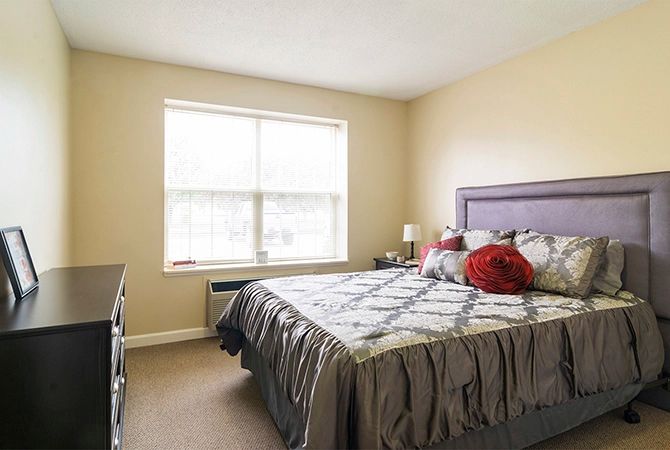 A cozy bedroom with a large bed and natural light from the window.