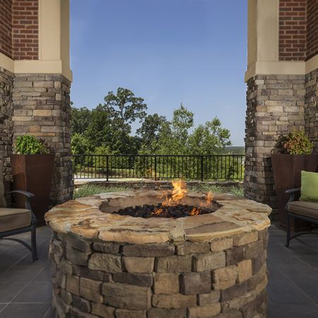 A cozy outdoor patio with a stone firepit and seating area overlooking a natural view.