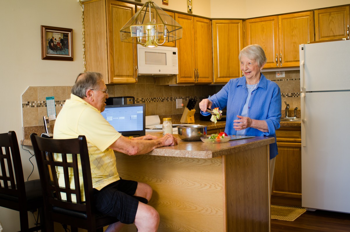 An elderly couple enjoying a moment together in the kitchen.