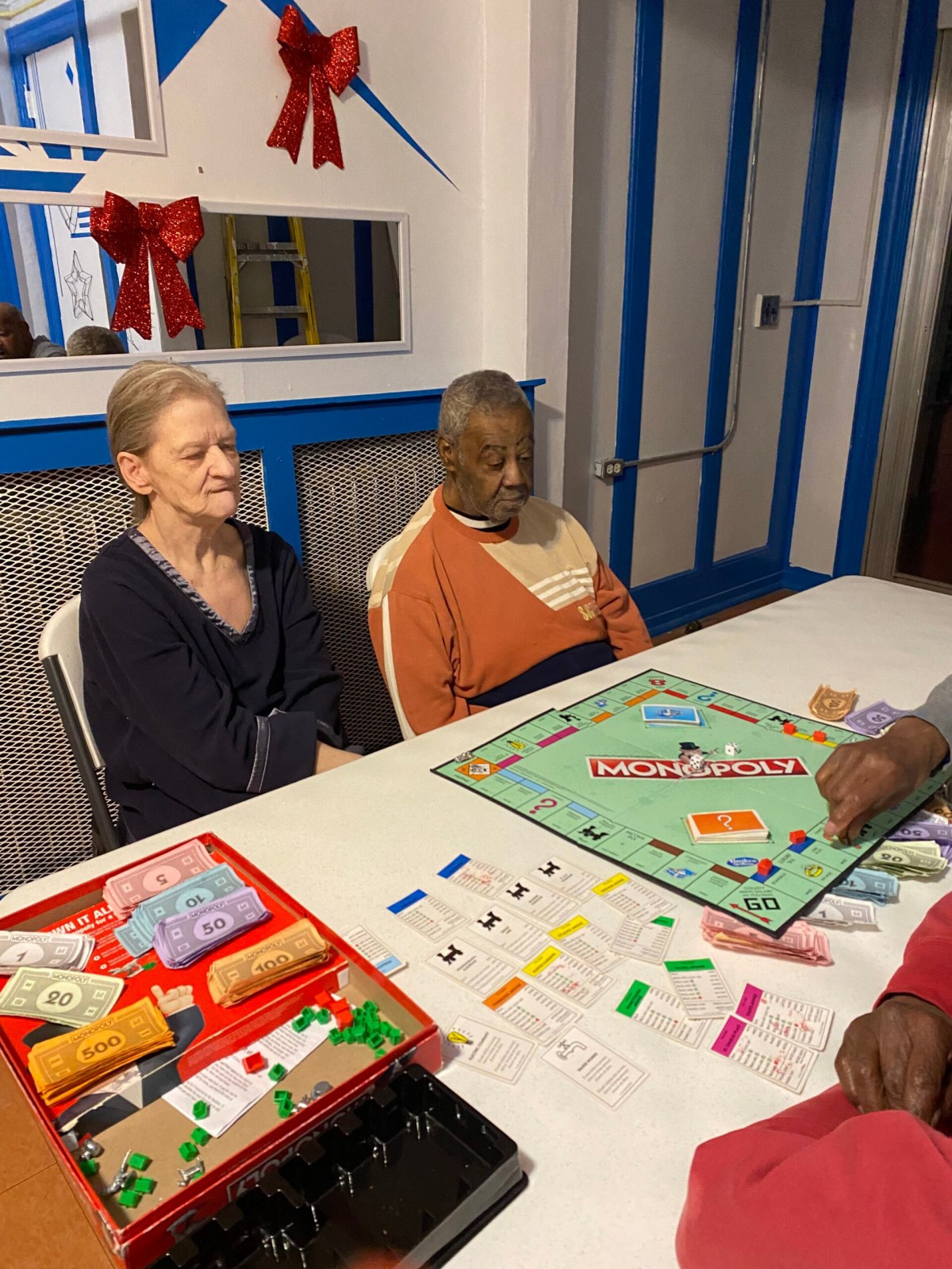 A group of people playing a game of Monopoly indoors.
