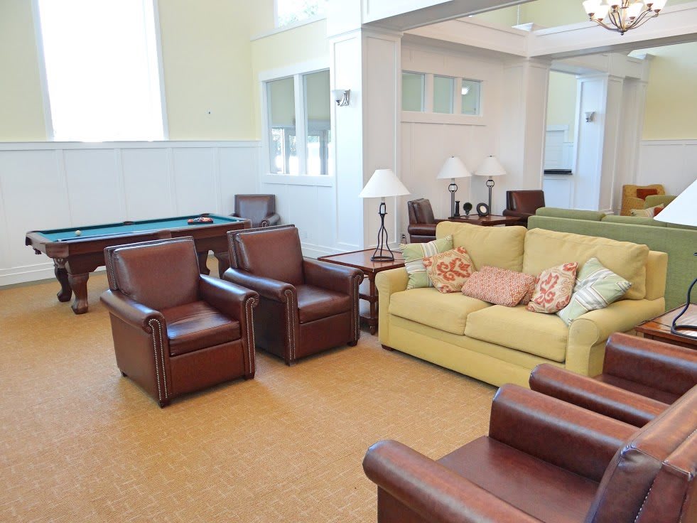 A cozy living room with a yellow sofa, leather armchairs, and various decor elements.