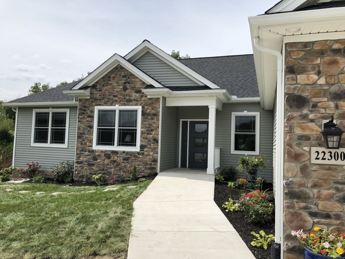 A modern residential house with stone facade and landscaped front yard.