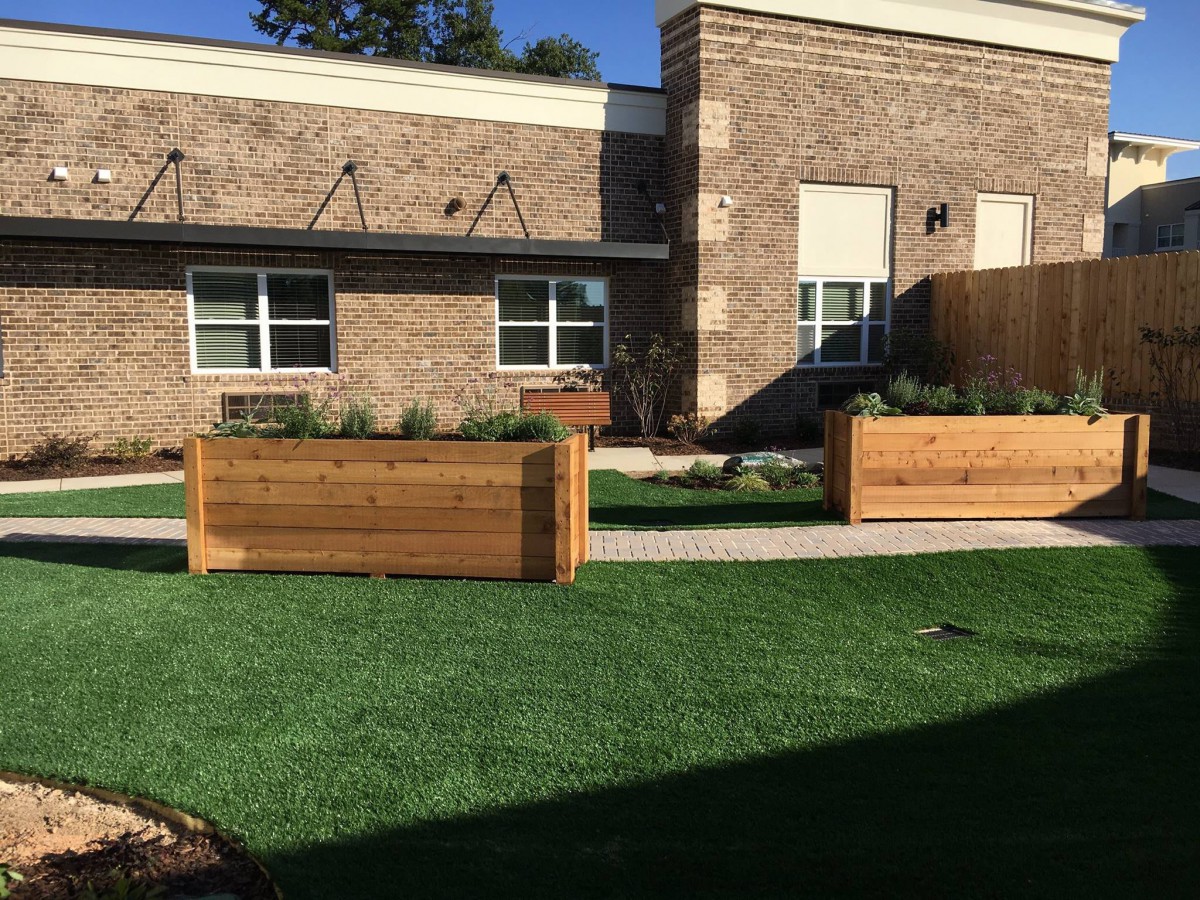 An outdoor space featuring wooden planters and a grassy area in front of a building.