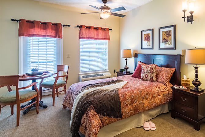 A cozy bedroom with a double bed, bedside lamp, and a small table with chairs.