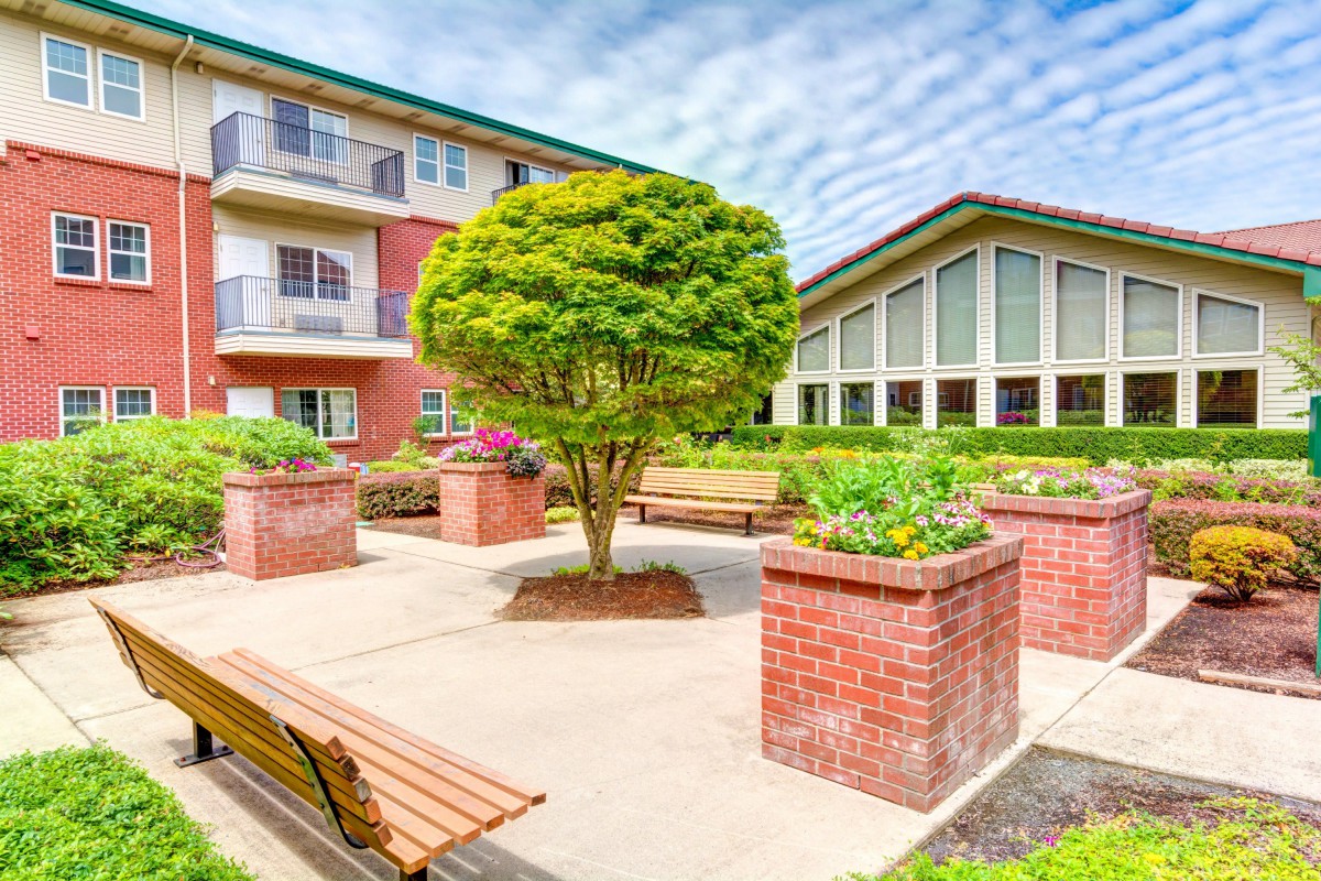 A well-maintained courtyard with benches and lush greenery, surrounded by residential buildings.