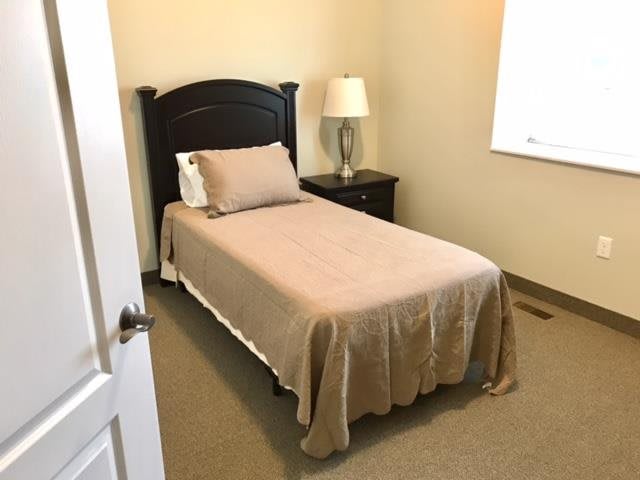 A minimalist bedroom with a single bed, nightstand, and lamp.