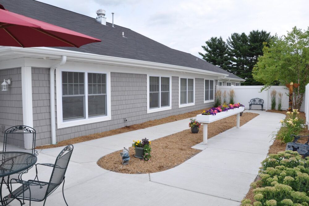 A backyard patio area with outdoor furniture and planters alongside a single-story house.