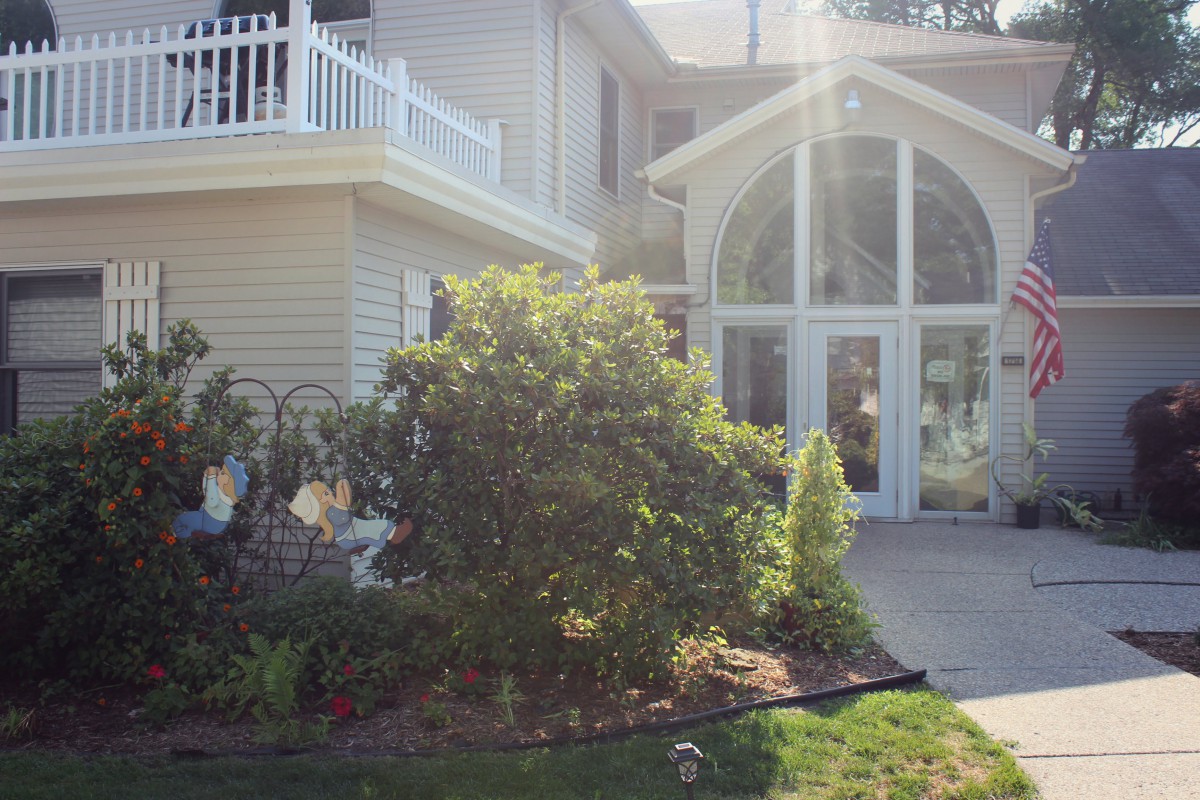 A suburban house with a garden and greenery in the front yard.