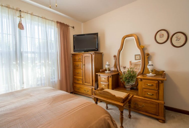 A cozy bedroom with wooden furniture, including a vanity table and a television.