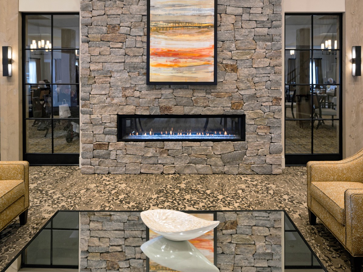 A modern living room with a stone wall fireplace and abstract artwork.