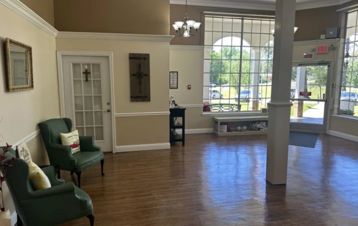 A spacious waiting area with large windows, comfortable seating, and wooden flooring.