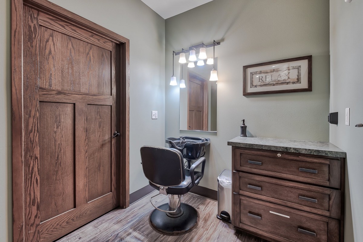 A rustic beauty salon setup featuring a barber chair, vanity, and ambient lighting.
