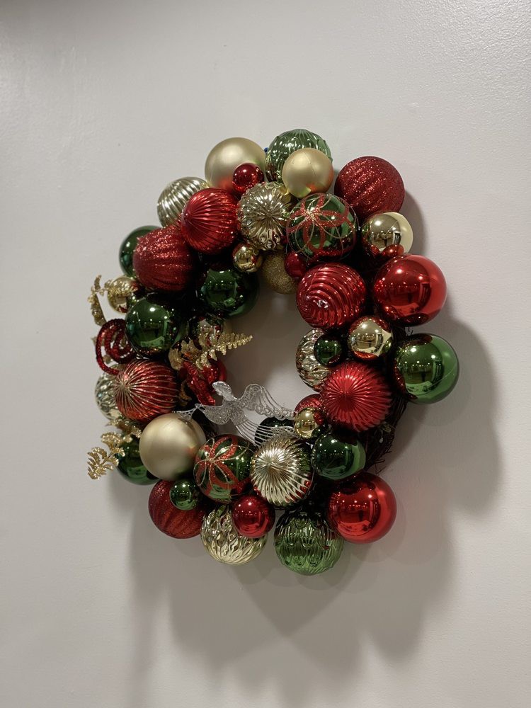 A festive Christmas wreath made of colorful ornaments in red, green, and gold.