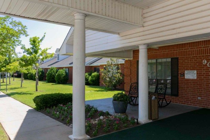A welcoming porch with columns and a landscaped garden in front of a building.