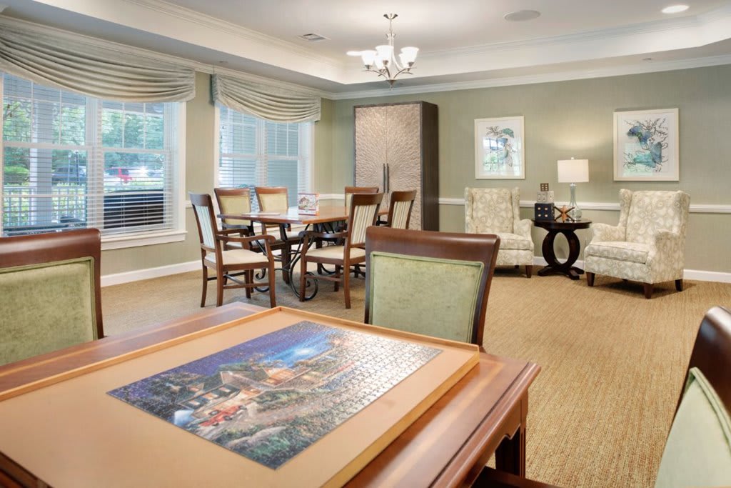 A cozy living room featuring a dining area with ample seating, elegant artwork, and large windows for natural light.