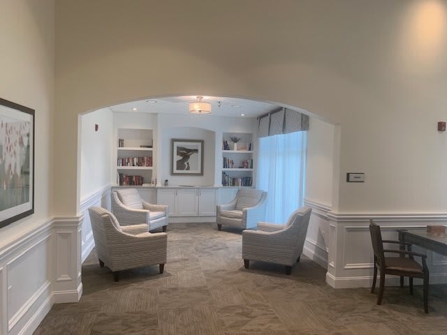 A cozy living room with neutral-colored chairs and built-in bookshelves, viewed through an archway.