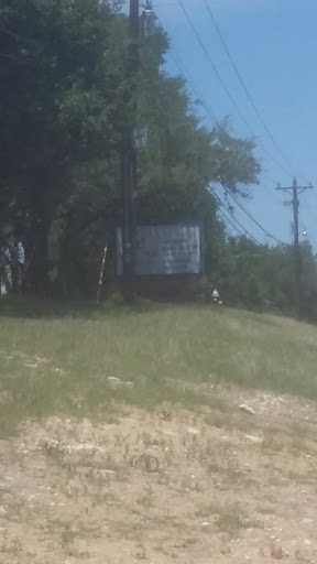 A distant view of a weathered sign amidst greenery and power lines.