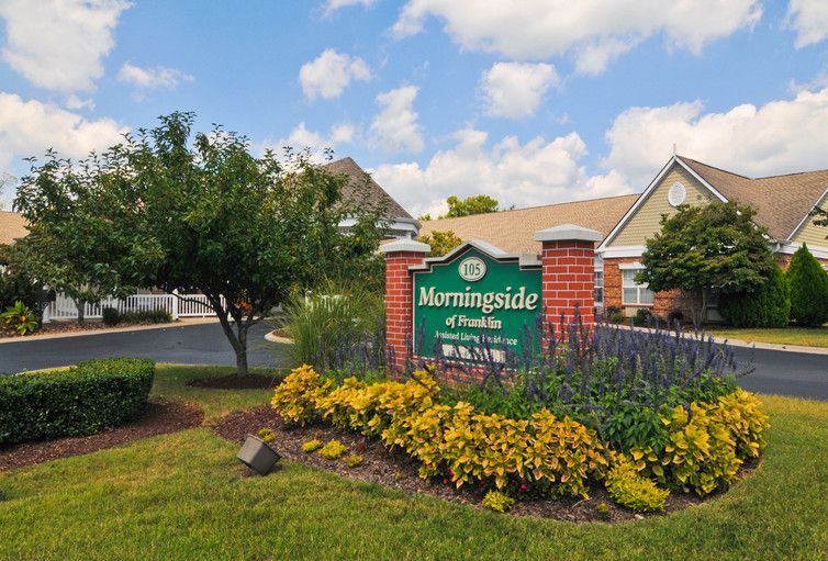 Entrance sign of a housing complex surrounded by well-maintained landscaping and flowers.