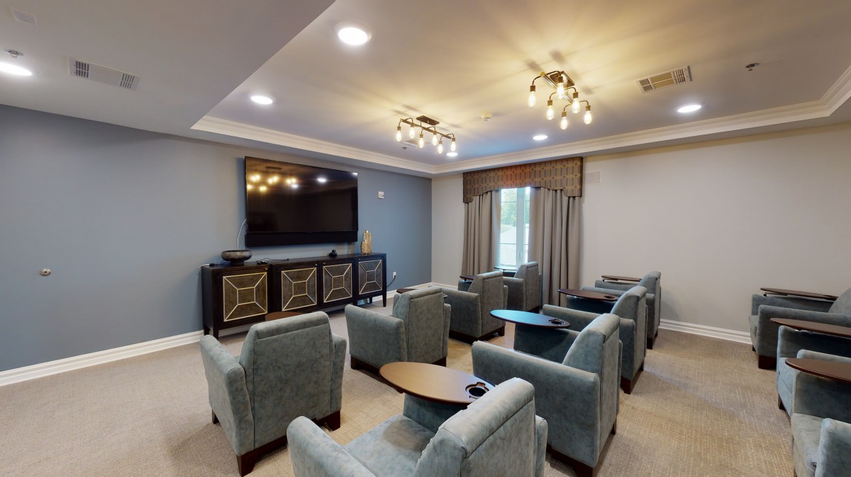 A cozy home theater room with plush seating and modern lighting, centered around a large television.