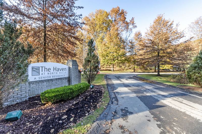 Entrance to a residential area surrounded by autumn trees.