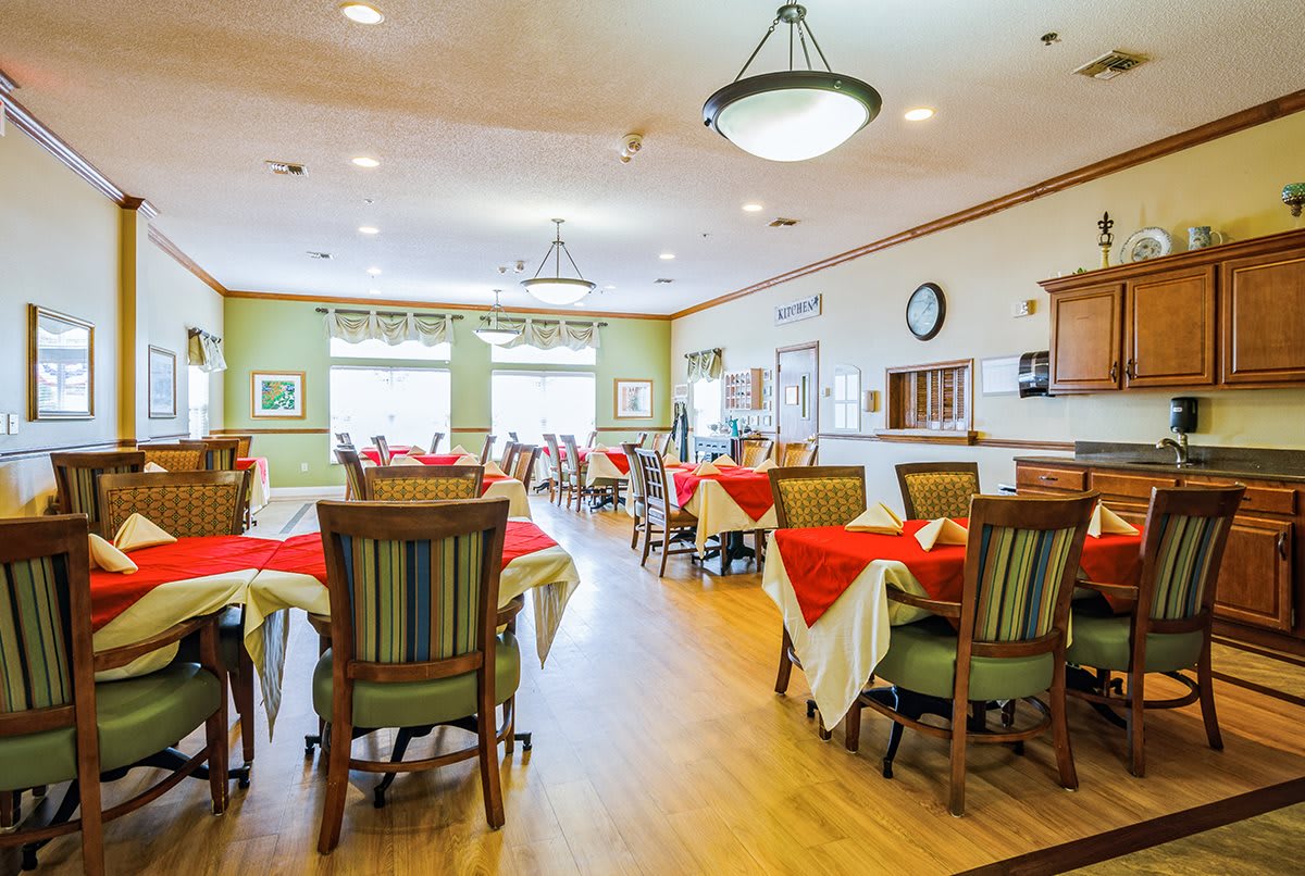 A brightly lit dining room with colorful table settings and empty chairs.