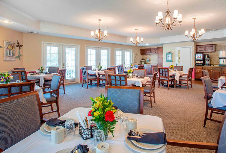 An elegant dining room with beautifully set tables, floral centerpieces, and chandeliers.