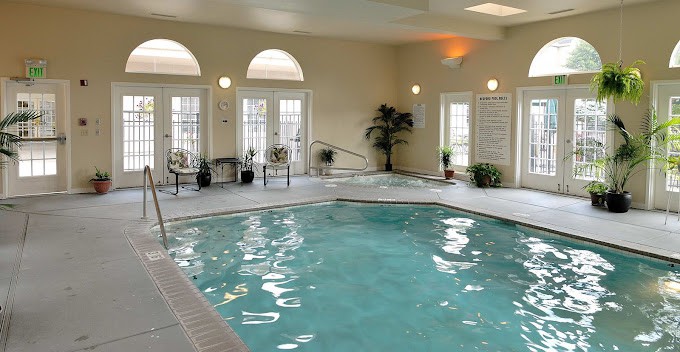 A luxurious indoor swimming pool area with seating and natural light.