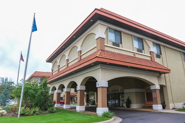 Exterior view of a hotel entrance with an arch design and flag displayed outside.
