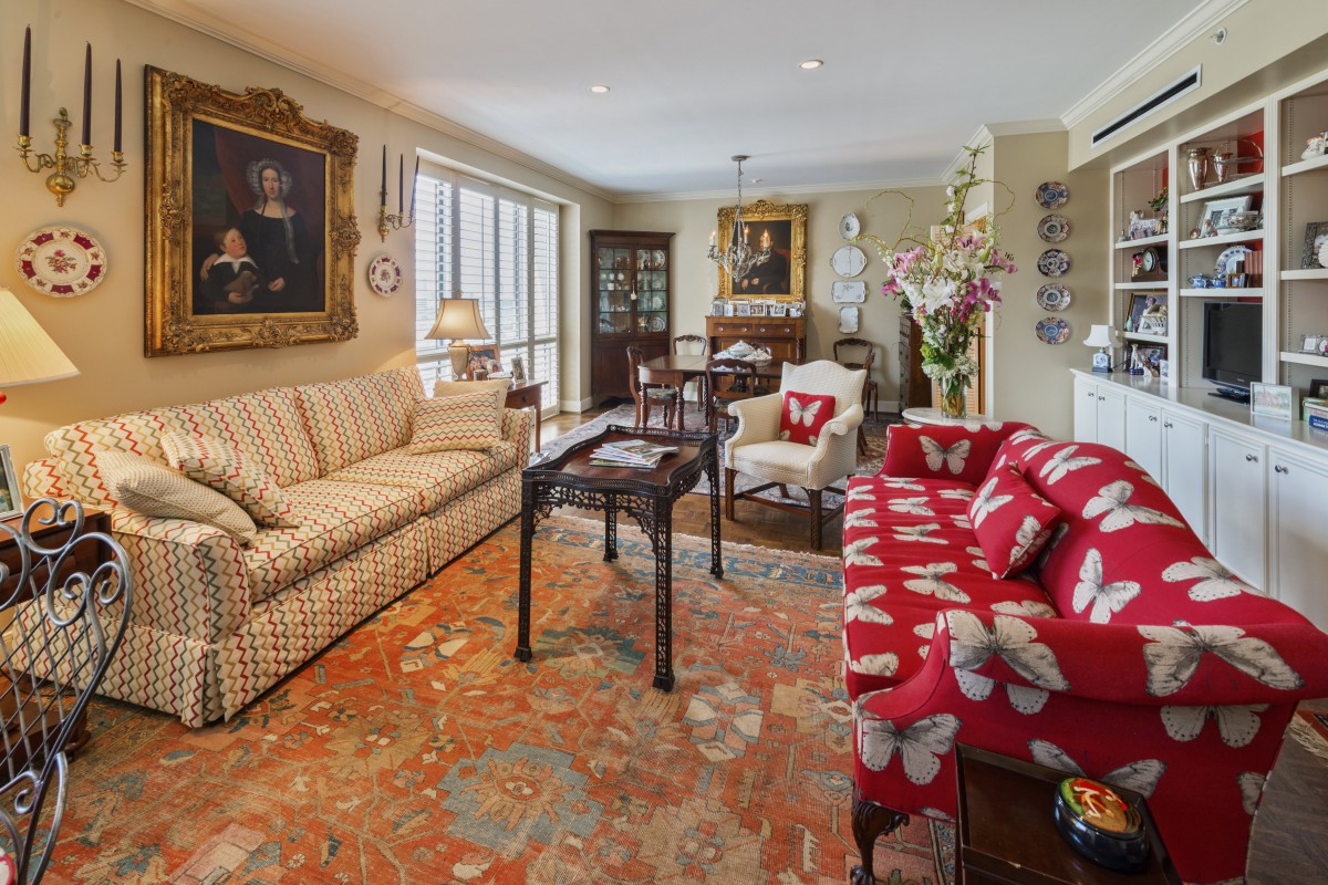 A cozy living room with traditional decor featuring patterned sofas, a large carpet, and elegant paintings.