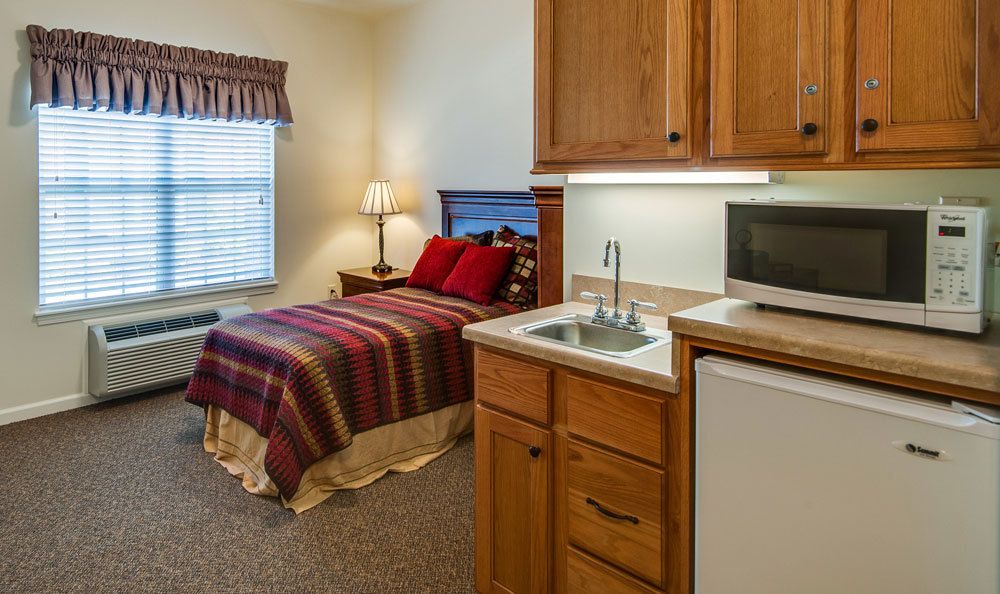 A cozy studio apartment with a bed, kitchenette, and warm decor.