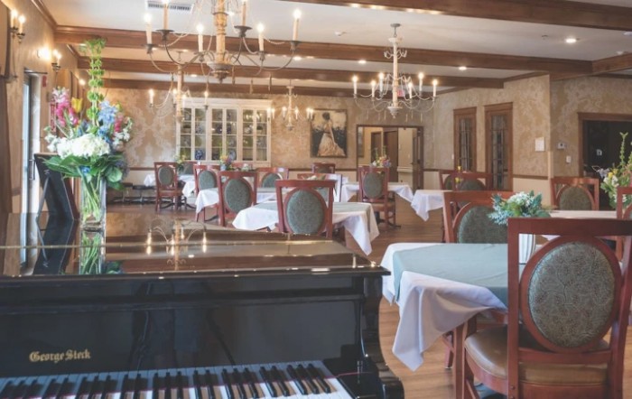 Elegant dining room with chandeliers and a grand piano.