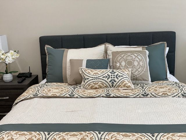 A neatly made bed with decorative pillows and a patterned comforter.