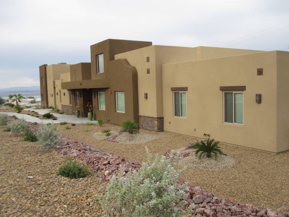 A modern southwestern-style stucco house surrounded by desert landscaping.