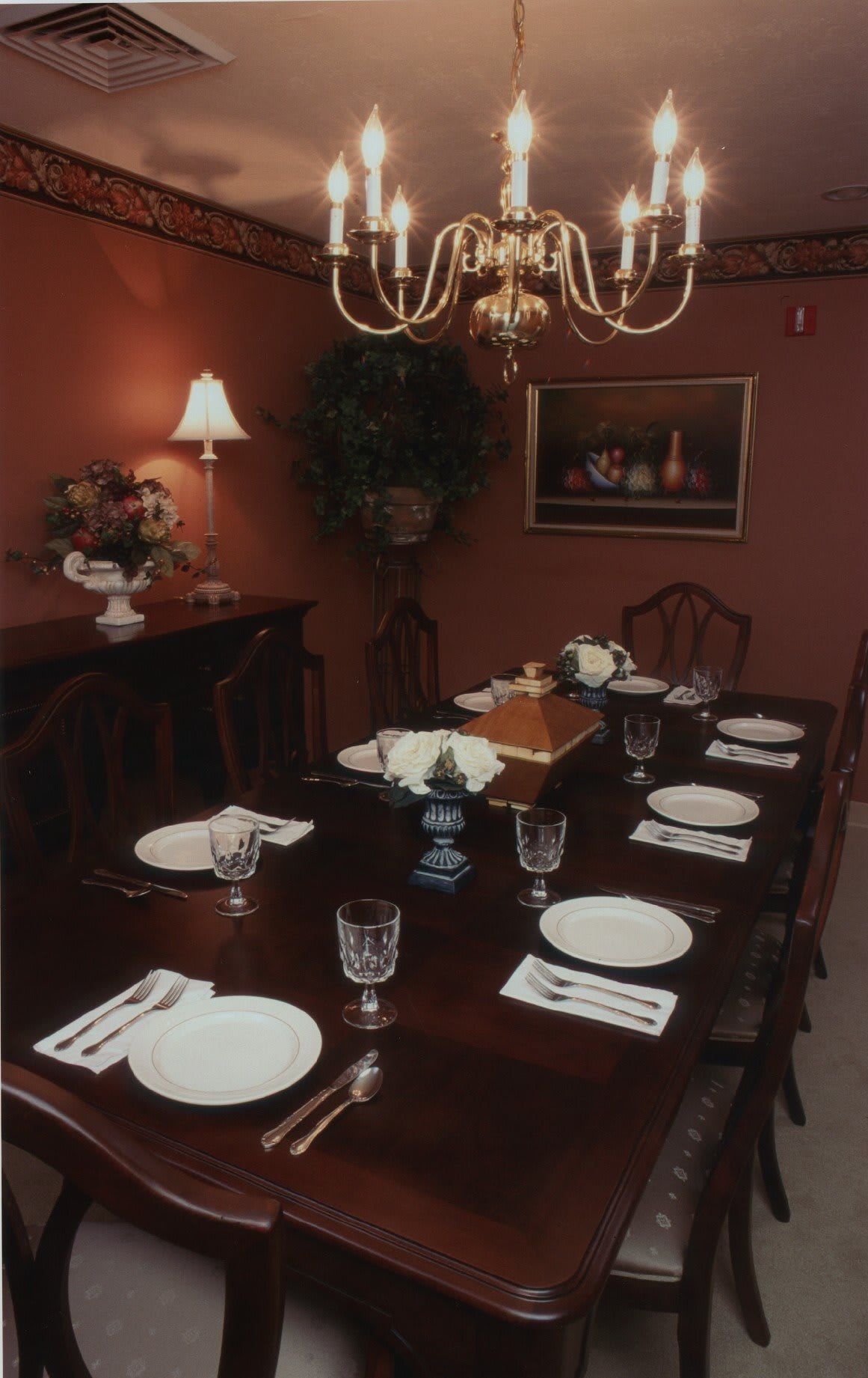 A formal dining room with an elegantly set table and a chandelier overhead.