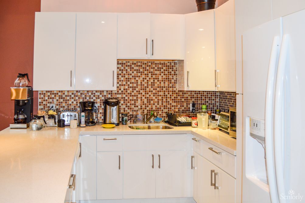 A modern kitchen with white cabinets and a patterned backsplash.