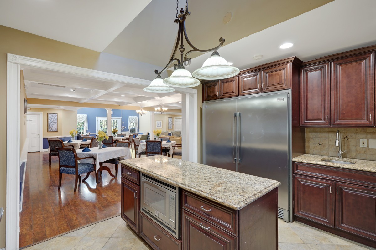 A modern kitchen featuring a granite countertop on the island, stainless steel appliances, and elegant chandelier lighting.