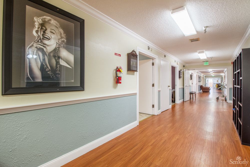 A well-lit hallway with wooden flooring, featuring artwork and multiple doorways.