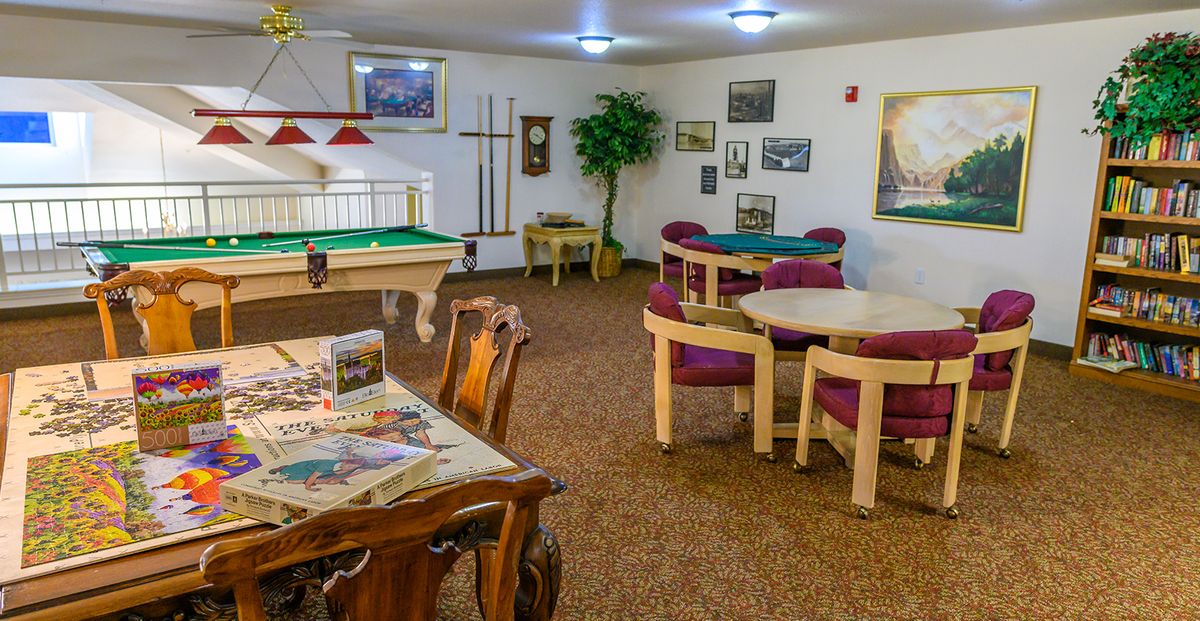A cozy game room featuring a pool table and card tables surrounded by decorative artwork.