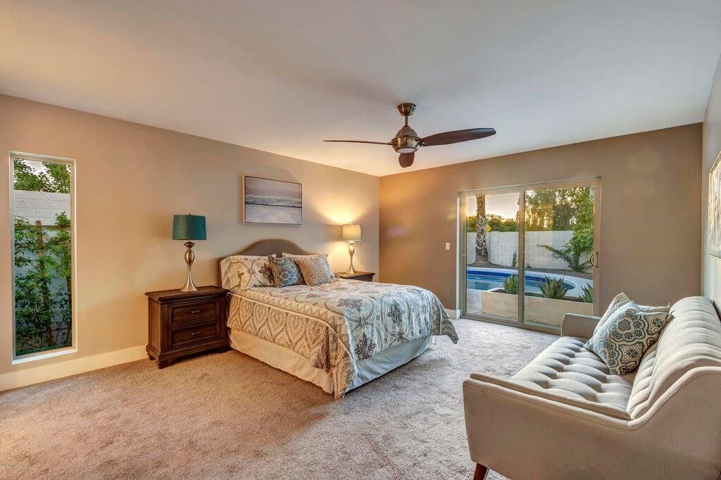 A modern bedroom with a comfortable bed, nightstands, and large windows offering natural light.